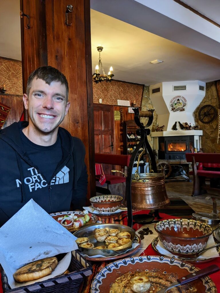 a man sits in a Bulgarian restaurant with a formidable amount of food in front of him. 