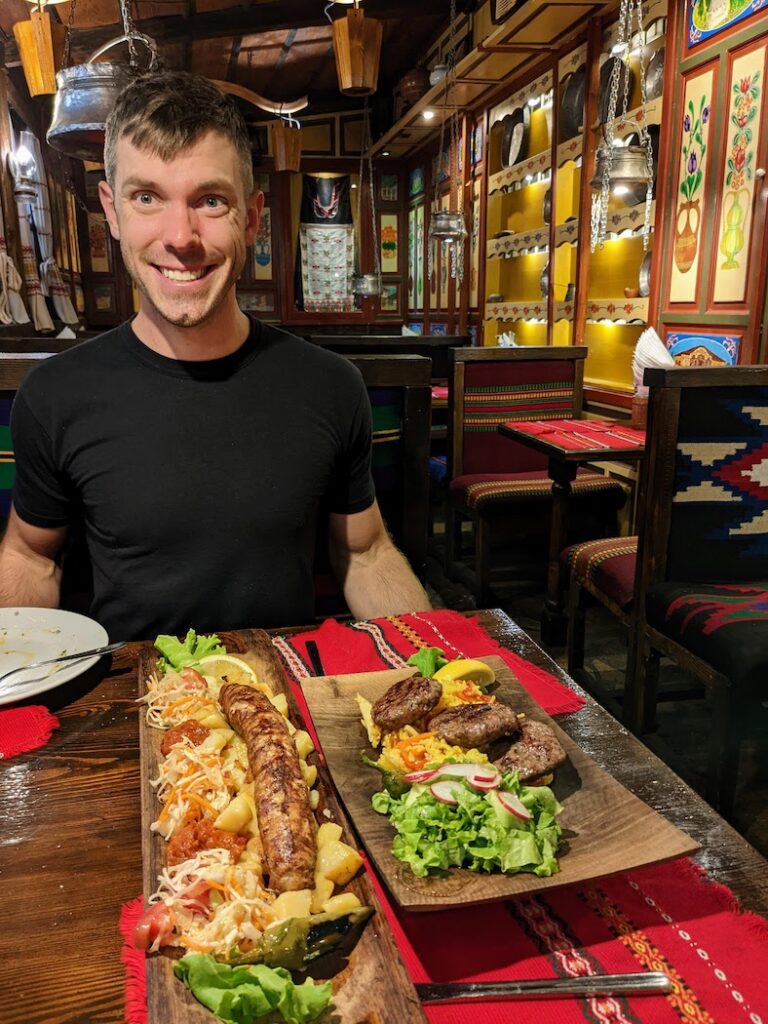 a man in a traditional bulgarian restaurant with two plates of food in front of him