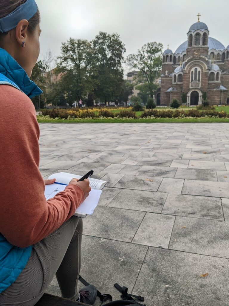 woman sitting in a courtyard drawing a local church in sofia bulgaria